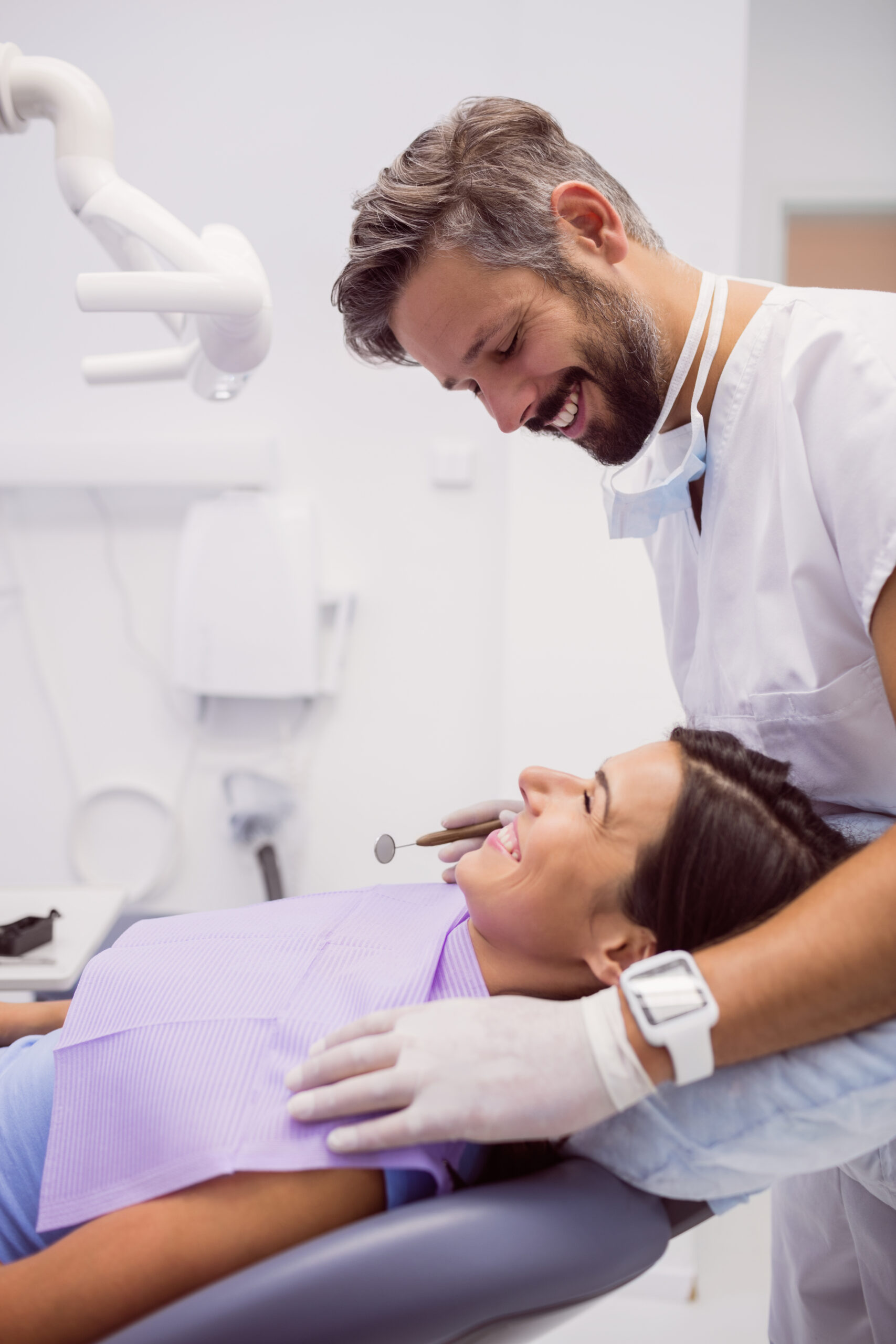 dentist smiling while examining patient in clinic